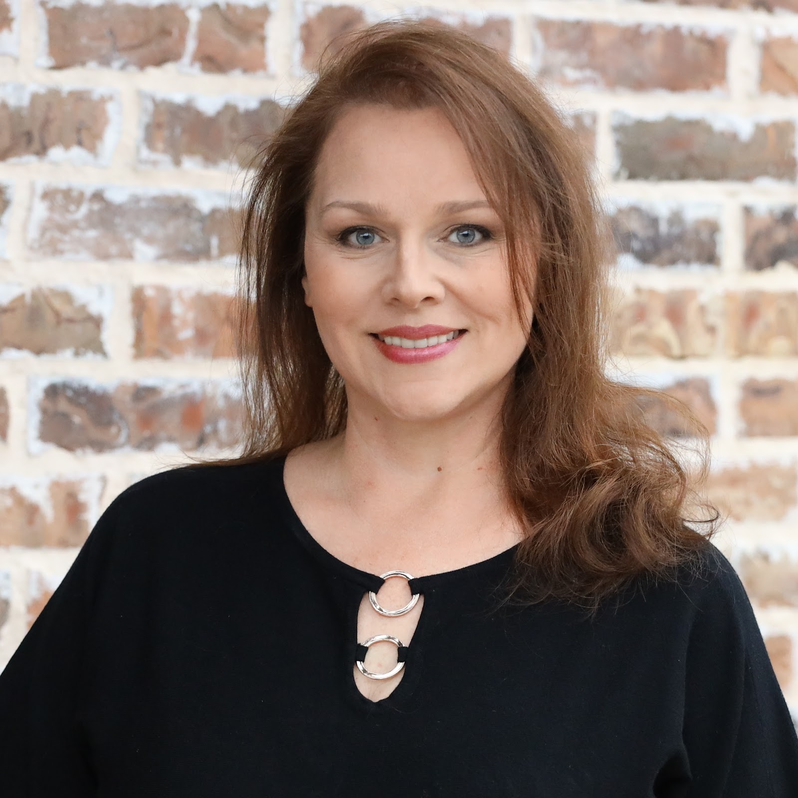 Mary Alexander smiling in front of a warm brick wall